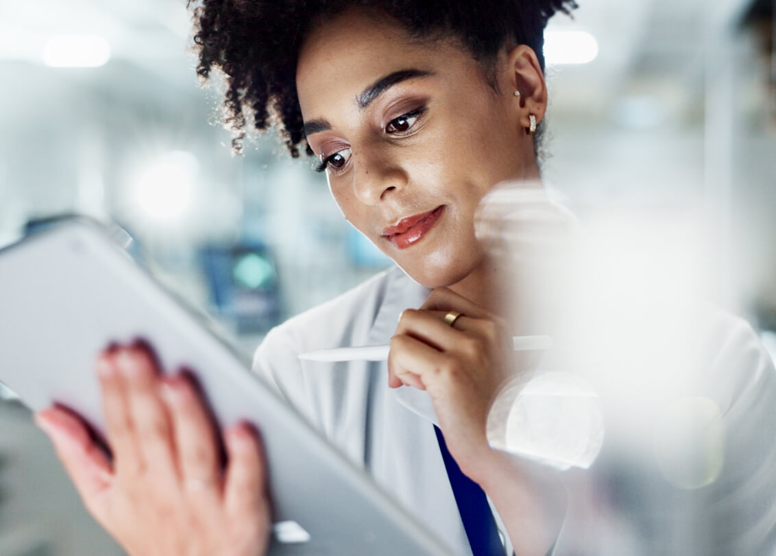 Diverse female clinical development professional using AI powered protocol design software on her tablet